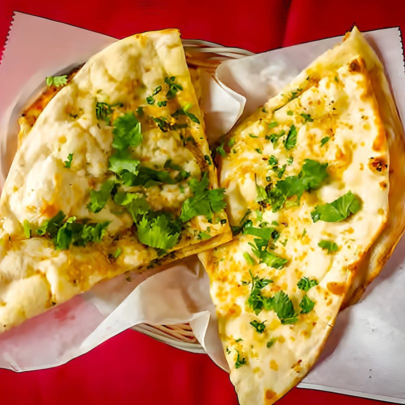 Two pieces of Mirch Masala's garlic naan, garnished with fresh cilantro, served in a basket.